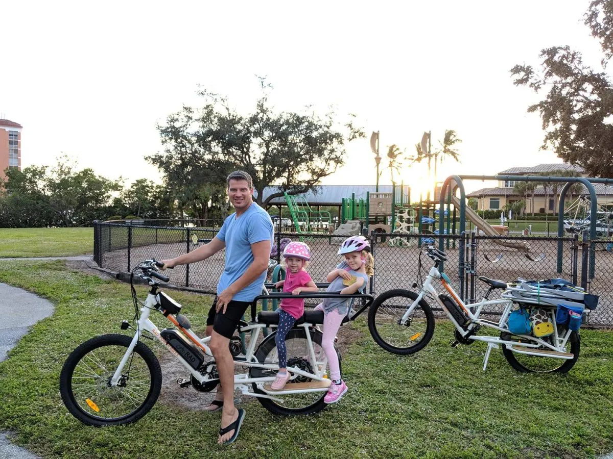 Scott Carr riding a Rad Power cargo e-bike with his kids at a Naples playground
